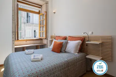 a bedroom with a bed with pillows and a window at Host Wise - Urban Stylish Flat - Ace Location in Porto