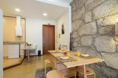a dining room with a table and a stone wall at Host Wise - Urban Stylish Flat - Ace Location in Porto