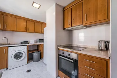 a kitchen with wooden cabinets and a washer and dryer at GuestReady - Miragaia Rooftop in Porto