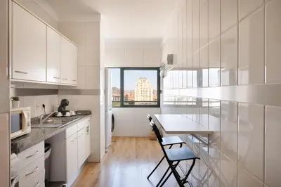 a kitchen with white cabinets and a table with chairs at Gaia Douro Apartment in Vila Nova de Gaia