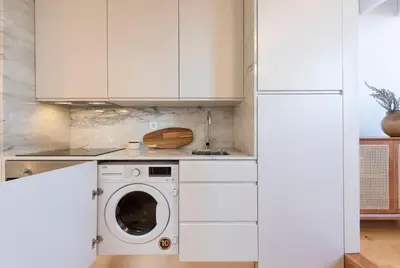 a washing machine in a kitchen with white cabinets at Tripas Coração Taipas Historical Center in Porto