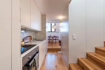 a kitchen with white cabinets and a wooden floor at Tripas Coração Taipas Historical Center in Porto
