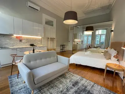a living room with a white bed and a kitchen at Formosa Apartments in Porto
