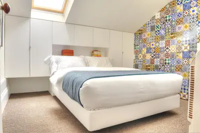 a bedroom with a white bed and a mosaic wall at Three Houses & Bedrooms in Porto