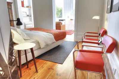 a bedroom with a bed and two chairs and a table at Three Houses & Bedrooms in Porto