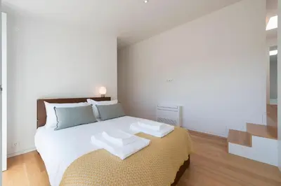 a bedroom with a large white bed and a staircase at Tripas-Coração, Santa Catarina in Porto