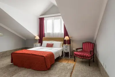 a bedroom with a bed and a red chair at Carpe Diem Apartments in Porto