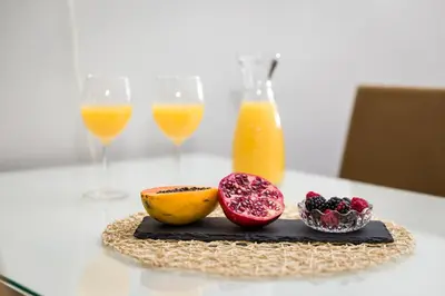 a table with a plate of fruit and two glasses of orange juice at Carpe Diem Apartments in Porto