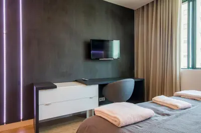 a bedroom with two beds and a desk with a tv on the wall at 418 Apartamento Galé wifi, estacionamento, elevador in Porto