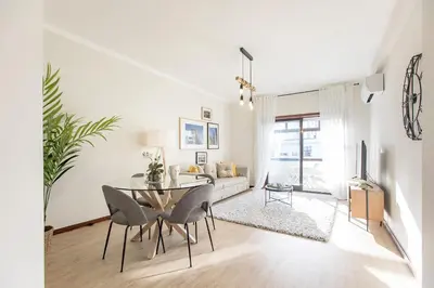 a white living room with a table and chairs at 2BR Flat in Bonfim w/ AC & Balcony by LovelyStay in Porto