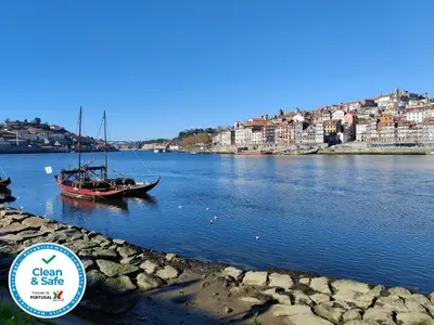 a boat in a river with a city in the background at Cais de Gaia Historic Loft in Vila Nova de Gaia