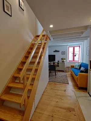 a staircase in a living room with a blue couch at Cais de Gaia Historic Loft in Vila Nova de Gaia