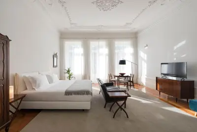 a white bedroom with a large bed and a tv at Habitat137 in Porto