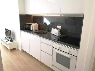 a kitchen with white cabinets and a black counter top at OportoView Prestige Apartment in Porto