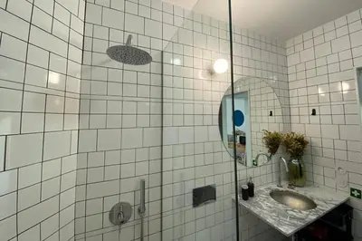 a white tiled bathroom with a sink and a mirror at Oxford Green House by LovelyStay in Porto