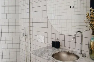 a white tiled bathroom with a sink and a mirror at Oxford Green House by LovelyStay in Porto