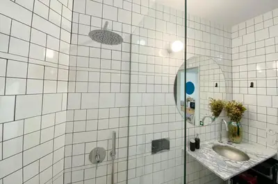 a white tiled bathroom with a sink and a mirror at Oxford Green House by LovelyStay in Porto