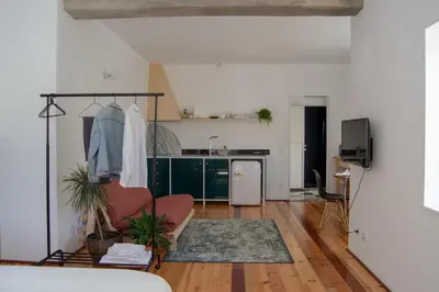 a living room with a chair and a kitchen at Oxford Green House by LovelyStay in Porto