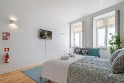 a white bedroom with a bed and two windows at Host Wise - Homely Noble Flats - Garden & Jacuzzi in Porto
