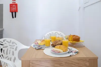 a table with a tray of breakfast foods and orange juice at Host Wise - Homely Noble Flats - Garden & Jacuzzi in Porto