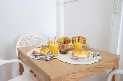 a wooden table with food and two glasses of orange juice at Host Wise - Homely Noble Flats - Garden & Jacuzzi in Porto