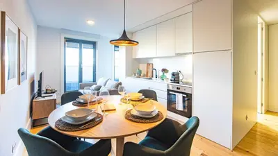 a kitchen and dining room with a wooden table and chairs at Stylish Studio w/ AC & Balcony by LovelyStay in Porto