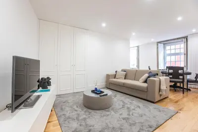 a living room with a couch and a tv at Elegant Downtown 1BR Flat w/ AC by LovelyStay in Porto