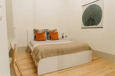 a white bedroom with a bed with orange pillows at Casa Burguesa Rua do Almada - Porto city center in Porto