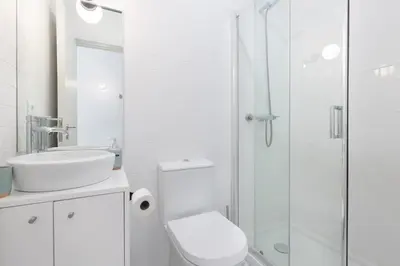 a white bathroom with a toilet and a shower at Vibrant flat by São Bento w/balcony - Loureiro140 in Porto