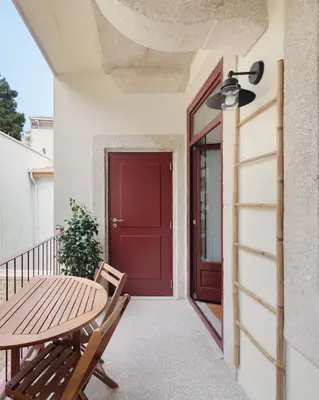 a patio with a red door and a table and chairs at Vibrant flat by São Bento w/balcony - Loureiro140 in Porto