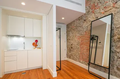 a kitchen with white cabinets and a brick wall at Porto River Infante in Porto