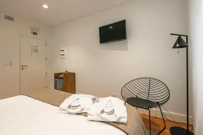 a bedroom with a bed and a chair and a television at Porto River Infante in Porto