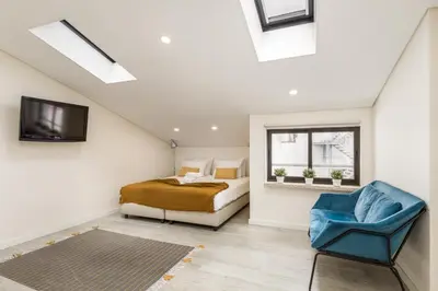 a attic bedroom with a bed and a blue chair at Center Liberty Apartment in Porto