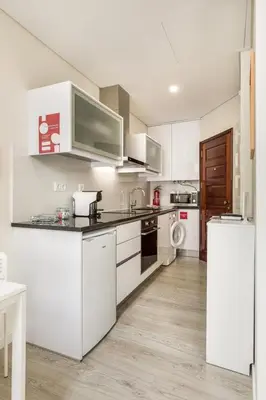 a kitchen with white cabinets and a white refrigerator at Center Liberty Apartment in Porto