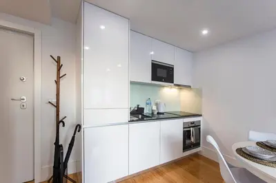 a white kitchen with a sink and a microwave at City Center 2BR Flat w/ AC by LovelyStay in Porto
