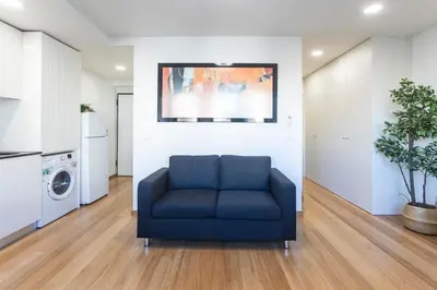 a blue couch in a living room with a kitchen at Homely Studio w/ AC near Marquês by LovelyStay in Porto