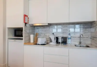 a kitchen counter with white cabinets and a sink at Habitatio - Aliados by LuxiStay in Porto