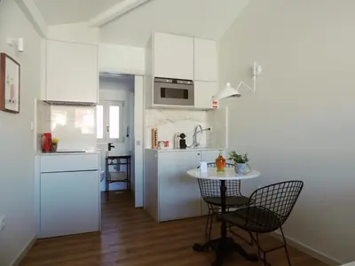a kitchen with white cabinets and a table and chairs at Maria da Sé Historic House in Porto