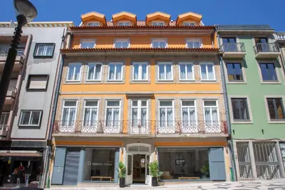 an orange building with white windows on a street at Casual Raízes Porto in Porto