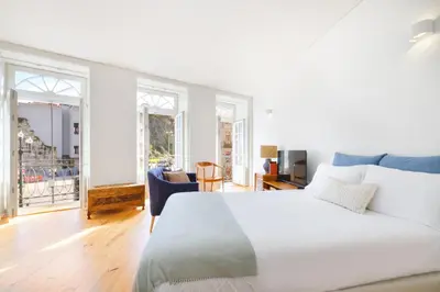 a white bedroom with a large white bed and windows at InBloom Apartments in Porto
