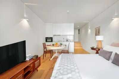a bedroom with a large bed and a kitchen at InBloom Apartments in Porto