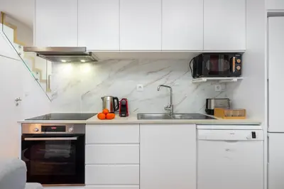 a kitchen with white cabinets and a sink at WHome Riverside View Premium Apartment w/ AC & Terrace in Porto