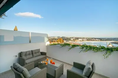 a balcony with couches and a table on a building at WHome Riverside View Premium Apartment w/ AC & Terrace in Porto