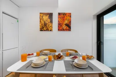 a white table with breakfast foods and orange juice at WHome Riverside View Premium Apartment w/ AC & Terrace in Porto