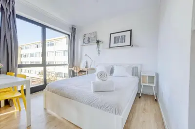 a white bedroom with a white bed and a desk at Travel & Live Alegria Apartments in Porto