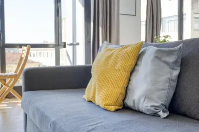 a yellow and gray pillow sitting on a couch at Travel & Live Alegria Apartments in Porto