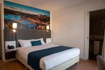 a bedroom with a large bed with a painting on the wall at Hotel Porto Interface Trindade By Kavia in Porto
