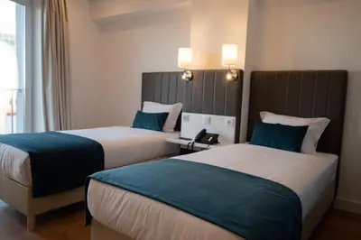 two beds in a hotel room with blue and white at Hotel Porto Interface Trindade By Kavia in Porto