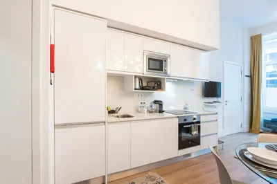 a white kitchen with white cabinets and a table at Elegant & Bright Flat by LovelyStay in Porto