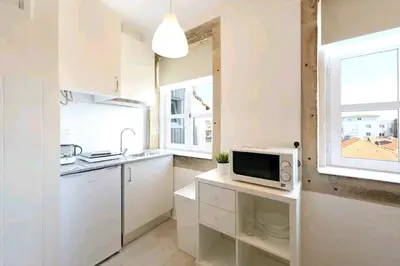 a kitchen with white cabinets and a microwave on a counter at Oporto Blue Liberdade - Central Studio with Amazing View and Kitchenette in Porto